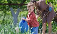 Dreng med vandkande i haven